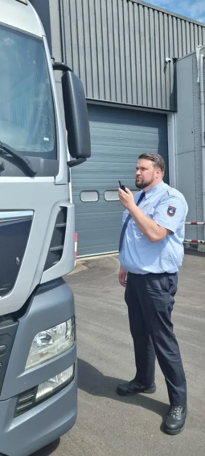bewaker met walkie talkie inspecteert vrachtwagen